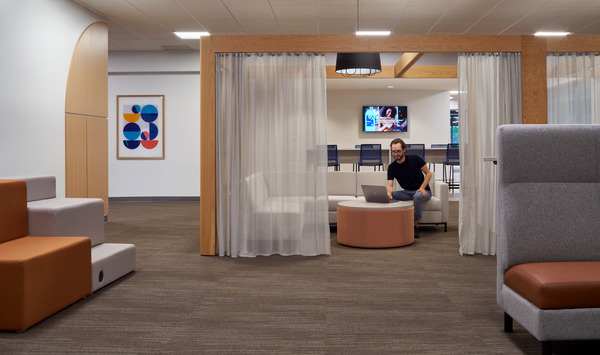 Corporate interior design featuring person sitting on couch with laptop.